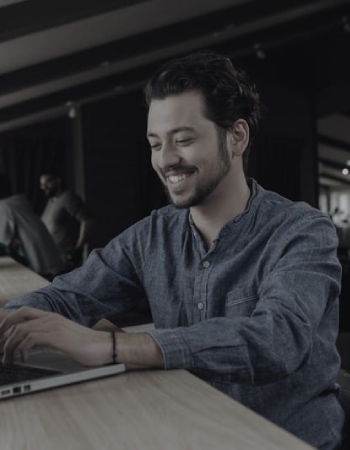 Aventis Digital team member smiling while working at a laptop – web design and SEO specialist on the Northern Beaches.